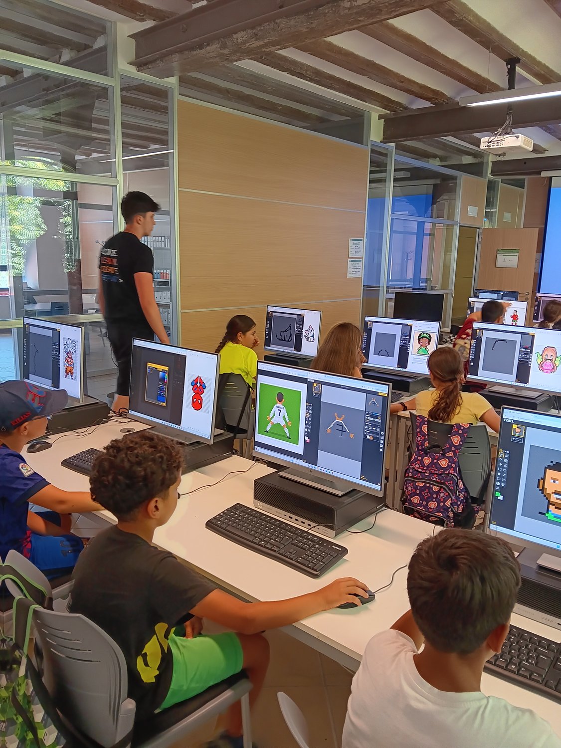 Un grup d'alumnes de Pixel Penedès treballant cadascun en el seu projecte de pixel art, amb un mentor supervisant la classe